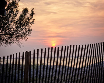 Silhouette fence against orange sky