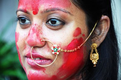 Close-up of woman with red face powder looking away while standing outdoors