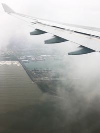 Cropped image of airplane flying over sea against sky