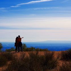 Full length of couple standing on cliff against sky