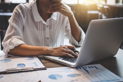 Midsection of businesswoman working on laptop in office