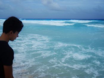 Boy standing on beach against sky