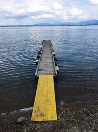Yellow jetty on lake against sky