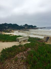 Scenic view of beach against cloudy sky