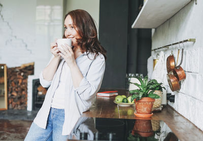 Woman wearing sunglasses standing against wall at home