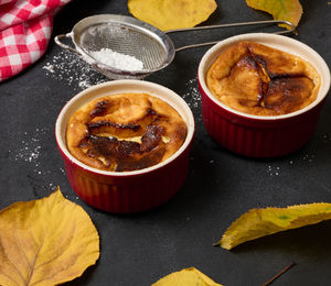 Cottage cheese dessert baked in portioned round ceramic plates on a wooden black table, top view