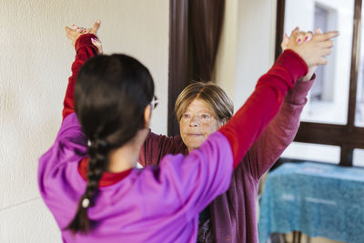 Young healthcare worker helping senior woman to exercise at home