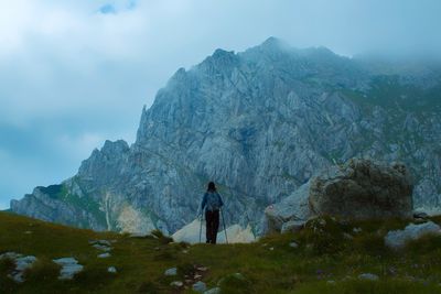 Rear view of man standing on mountain against sky