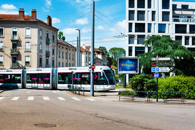 Road by buildings in city against sky