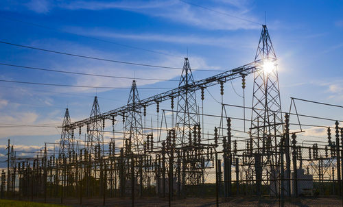 Low angle view of electricity pylon against sky during sunset