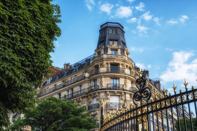 Paris classic apartment building view with typical parisian balconies and rooftiles.