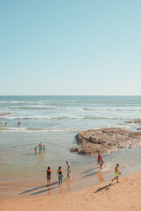 People on beach against clear sky