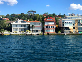 Buildings by sea against blue sky