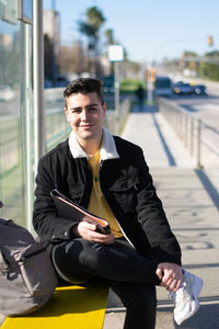 Smiling young man sitting in city