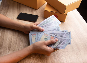 Midsection of person holding paper with text on table