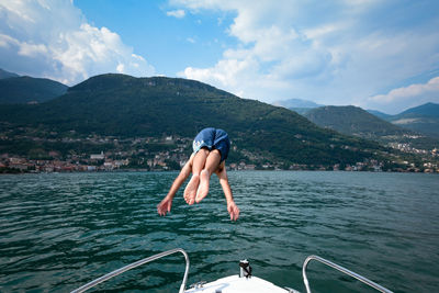 Full length of man jump to lake against mountains