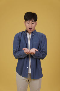 Young man standing against yellow background