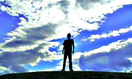 Low angle view of people standing against cloudy sky