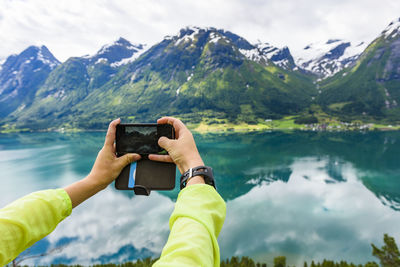 Person photographing mountains and lake