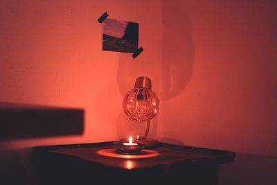 Close-up of illuminated light bulb on table against wall