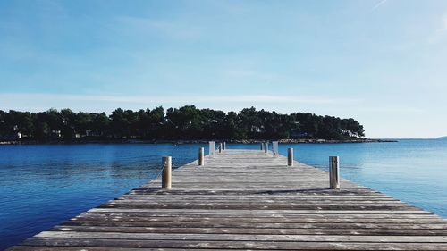 Wooden pier over sea against blue sky