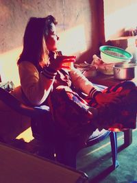 Side view of woman sitting on table at home