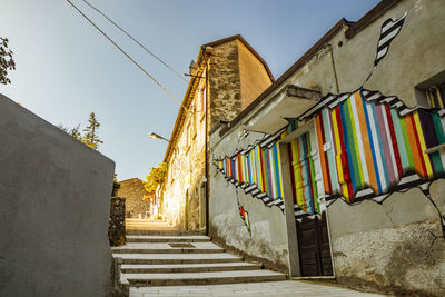 Low angle view of staircase amidst buildings against sky