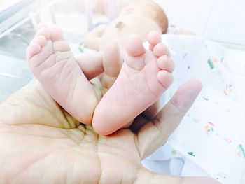 Low section of baby lying on bed