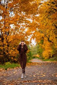 Young beautiful woman in long coat on the country lane in autumn