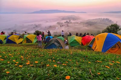 Group of people on field against sky during sunset