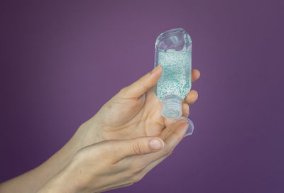 Close-up of hand holding glass against blue background