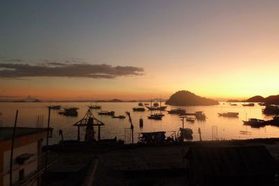 Silhouette boats in sea against sky during sunset