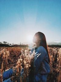 Side view of woman standing against blue sky