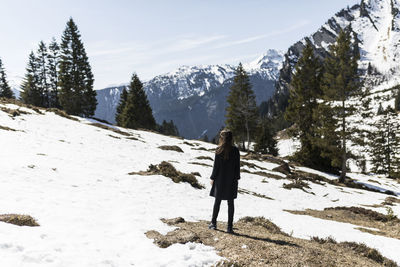 Woman standing on snowy field against mountains