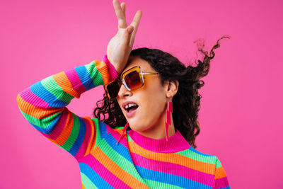 Portrait of woman with arms raised against yellow background