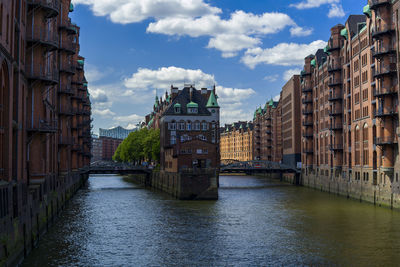 Canal amidst buildings in city against sky