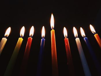 Low angle view of lit candles against black background