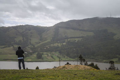 Rear view of man standing on mountain against sky