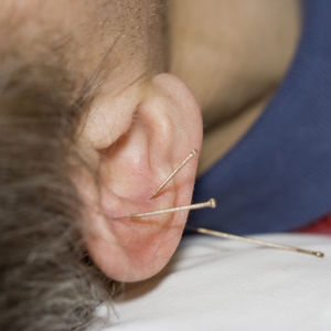 Cropped ear of man with needle