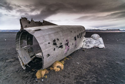 Abandoned boat on beach against sky