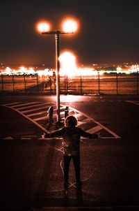 Rear view of man standing on road at night