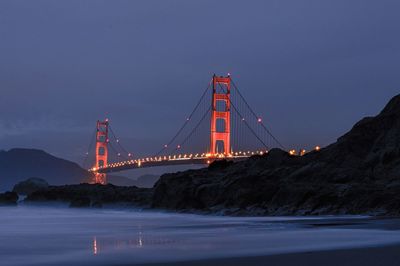 Illuminated golden gate bridge against cloudy sky at dusk 