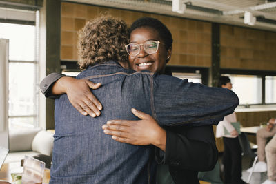 Smiling businesswoman embracing male colleague at office