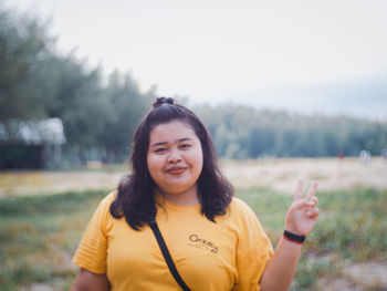 Portrait of smiling young woman standing on field