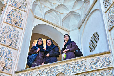 Low angle view of friends sitting outside building