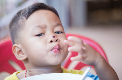 Portrait of cute boy with nose injury eating food while sitting at home