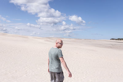 Man on sand dune in desert against sky