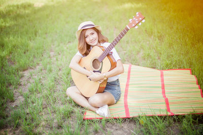 Young woman with guitar on grassy field at park