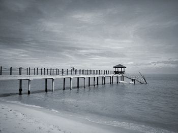 Wooden posts on beach against sky