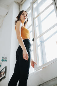 Low angle view of woman standing by window at home